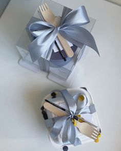 two forks and spoons in a gift box with silver ribbon on the top one