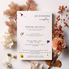 the wedding stationery is surrounded by dried flowers and foliage, including an orange rose