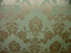 an old wallpaper with gold and green flowers on it's side, as well as the background