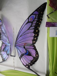 two purple butterflies sitting on top of a white sheet next to a green chair and wall