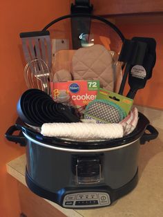 a crock pot filled with cooking utensils and other kitchen items sitting on top of a counter