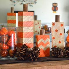 pine cones and pumpkins are arranged in front of wooden blocks with chevron stripes