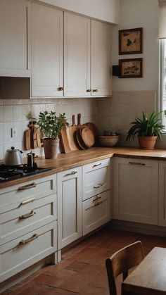 a kitchen filled with lots of white cabinets and wooden counter tops next to a window