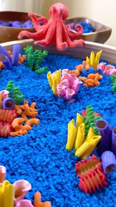 an octopus plays with plastic toys in a play area that looks like it is made out of sand