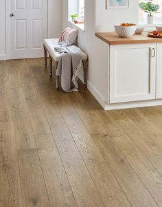 a wooden floor in a kitchen with white cabinets and wood counter tops on the side