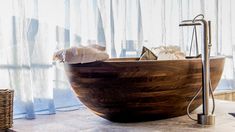 a large wooden bathtub sitting on top of a tiled floor next to a window