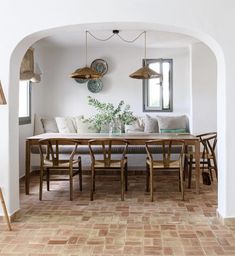 an archway leads into a dining room with white walls and flooring, along with wooden chairs