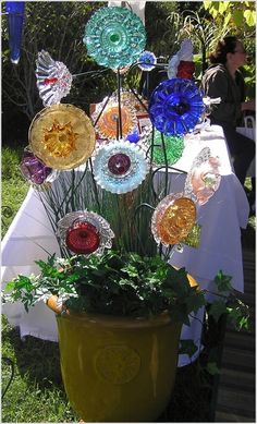 a potted plant sitting on top of a table covered in colorful glass plates and flowers