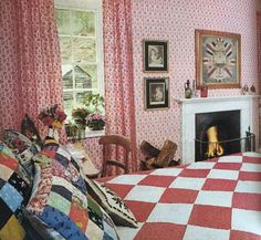 a bedroom with pink and white checkered bedspread, fireplace, pictures on the wall