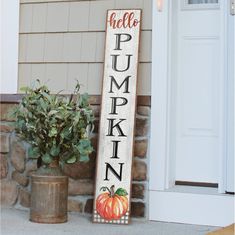 a wooden sign that says hello pumpkin on it next to a potted plant and door