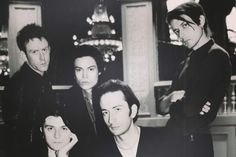 black and white photograph of four men in front of a bar with one man looking at the camera