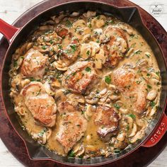 a skillet filled with meat and mushrooms covered in gravy on top of a wooden table