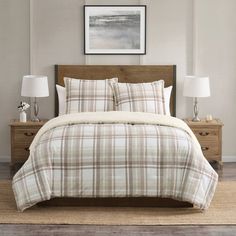 a bed with plaid comforter and pillows in a white room next to two nightstands