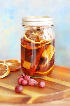 a jar filled with sliced oranges on top of a wooden cutting board next to some fruit