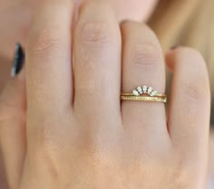 a close up of a person's hand wearing a gold ring with three diamonds