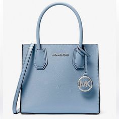 a blue michael kors handbag with a metal logo on the front and side