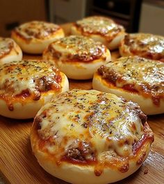 several mini pizzas with cheese and sauce on a cutting board