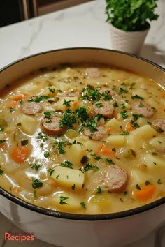 a bowl of soup with sausage, potatoes and carrots