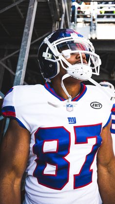 a football player is wearing a helmet and standing in the bleachers with his hand on his hip