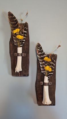 two wall hangings with flowers and feathers on the top one is made out of wood