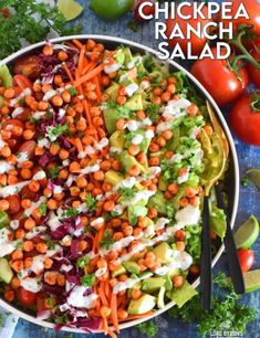 a salad with carrots, lettuce and tomatoes in it on a blue table