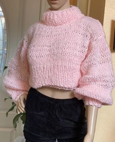 a mannequin wearing a pink sweater and black pants with her hands on her hips