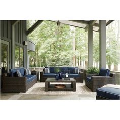 an outdoor living room with blue furniture and large trees in the backgroung