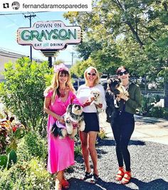 three women standing in front of the grayson sign and holding their puppies while posing for a photo