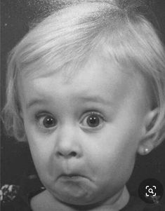 a black and white photo of a toddler making a face