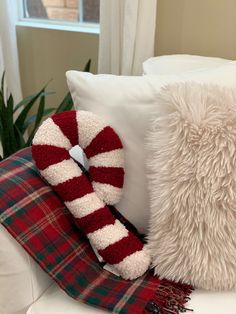 a white couch with two pillows and a scarf on it's back, sitting next to a pillow