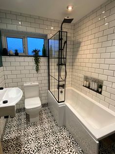 a white bathroom with black and white tile flooring on the walls, tub, toilet and sink