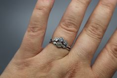 a woman's hand with a diamond ring on top of her left hand,