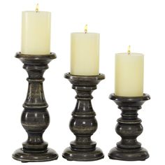 three tall candles sitting next to each other