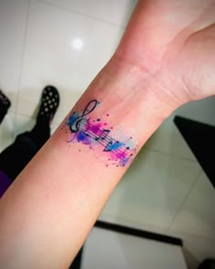 a person's arm with a colorful tattoo on the left side of their wrist