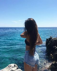 a woman standing on top of a rock next to the ocean