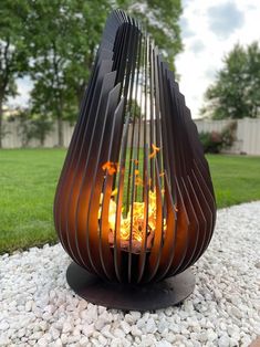 a fire pit sitting on top of a gravel covered ground next to a lush green field