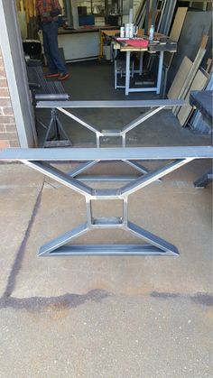 a metal table sitting on top of a cement floor next to a building with people in the background