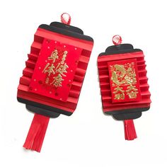 two red and black paper lanterns with chinese characters on them, one is holding a string