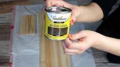 a person holding a can of wood stain