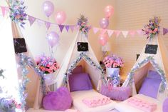 a room decorated in pink and purple with balloons, bedding, pillows and stuffed animals