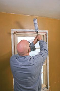 a man with a paint roller on his head painting the wall in an empty room