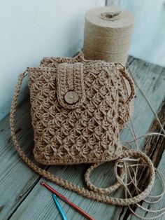 a crocheted purse sitting on top of a wooden table next to yarn and scissors