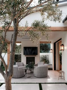 an outdoor living area with couches, chairs and a television mounted on the wall