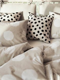 a bed topped with lots of pillows covered in polka dot sheets and pillow shampoos