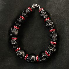 "If you're like me, you love skulls. So show your love with this skull bracelet! This bracelet features black howlite stone skulls and red stone crystal spacers, and is closed with a silver stainless steel lobster claw clasp. It comes in 3 sizes: Large - Fits wrists you to 7 1/2\" around Medium - Fits wrists up to 6 1/2\" around Small - Fits wrists up to 5 1/2\" around. If you need a different size, let me know and I will see what I can do. Make sure to check out my shop, PopBangBoom, for all so Black Rock Style Jewelry For Halloween, Black Rock Style Bracelet For Gift, Edgy Black Beaded Jewelry, Black Gothic Bracelets With Skull Print, Gothic Black Beaded Bracelets For Halloween, Red Beaded Bracelets For Halloween Gift, Punk Style Black Beaded Bracelets For Gift, Adjustable Red Beaded Bracelets For Halloween, Black Beaded Gothic Bracelets