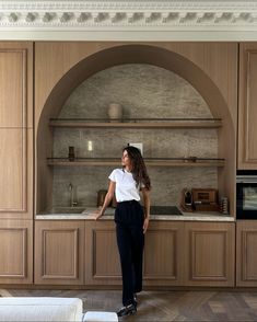 a woman standing in front of a kitchen counter with an oven and microwave behind her