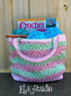 a crocheted bag sitting on top of a wooden table next to a book