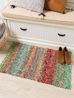 a pair of brown shoes sitting on top of a colorful rug next to a bench