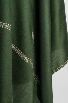 Immerse yourself in the elegance of this deep forest green merino wool scarf, beautifully hand-embroidered with intricate Sozni floral motifs. The subtle blossom patterns are carefully placed to enhance the simplicity of the design while showcasing the artistry of Kashmiri craftsmanship. This lightweight and soft scarf offers a timeless charm, perfect for both casual and formal wear. The delicate embroidery along the borders adds a refined touch, making it a graceful addition to any wardrobe, id Bohemian Green Pashmina Shawl In Traditional Drape, Green Embroidered Bohemian Shawl, Green Floral Embroidered Fabric For Eid, Eid Green Floral Embroidered Fabric, Festive Bohemian Pashmina Shawl With Floral Embroidery, Green Shawl With Resham Embroidery In Traditional Drape, Bohemian Embroidered Green Dupatta, Bohemian Green Traditional Wear With Embroidered Border, Green Bohemian Dupatta With Floral Embroidery