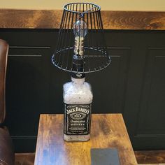 a bottle sitting on top of a wooden table next to a brown leather chair and lamp